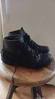 Side view of men's black slip and oil resistant crew shoes size 8.5 on wooden stool.