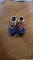 Pair of size 5 Nike women's running shoes with blue and pink colors on a wooden floor.