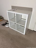 White 4-cube shelving unit placed on carpeted floor against wall