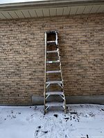 Photo of full 95-inch Keller aluminum ladder standing against a brick wall outdoors with snow on the ground and some rust on one side.