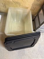 View inside one clear plastic tote with black lids stacked beside it