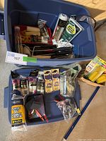 Blue Rubbermaid Roughneck bin filled with various painting tools including rollers, pyramids, rags, trays, brushes, and accessories.