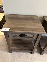 Front and partial side view of Sauder County Line Collection side table/night stand showing drawer with dark Spanish cup pull and open lower shelf with Salt Oak finish