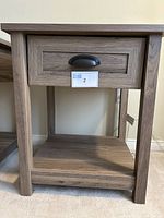 Front view of the Sauder side table showing drawer with black hardware and lower shelf