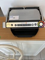 Frontal view of the Tfal OptiGrill showing control panel with cooking mode icons and temperature dial