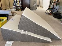 Two triangular wedge pillows stacked, showing grey jacquard sides and white memory foam tops, with tags visible.