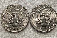 Reverses of two 1973 USA half dollar coins showing the presidential seal with eagle and inscriptions 'UNITED STATES OF AMERICA' and 'HALF DOLLAR'.