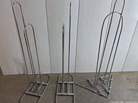 Photo showing all three metal commercial hanger stackers with rectangular bases against white background.