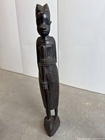 Handcarved wooden male figure with staff, standing on a base, carved in African tribal folk art style.