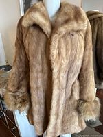 Front view of the light brown fur coat with visible buttons and collar.