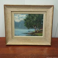 Full front view of the antique oil painting in its frame, showing the lakeside scene with trees and boat.
