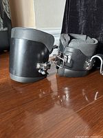 Side view of a black inversion boot showing padded interior and metal latch mechanism on the side