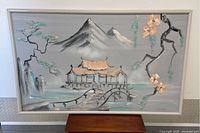 Full view of large rectangular oil painting on canvas with oriental landscape scene including mountains, bridge, pavilion, trees, and waterfall in muted grays, turquoise, and peach tones framed in a wooden frame.
