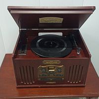Front view of the wooden console stereo showing the turntable under the open lid and front cassette/CD player controls with speaker grills.