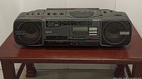 Front view of Sanyo portable stereo system with speakers and control panel on a wooden table
