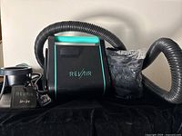 Photo of Revair main unit, flexible hose, power cord, base stand, and mesh bag on black background.