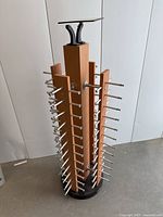 Full view of the wooden glasses display stand showing four vertical panels with multiple metal pegs for hanging glasses.