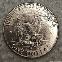 Close-up of reverse side of 1972 Eisenhower dollar coin showing flying eagle clutching olive branch with inscriptions around edge