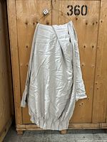 Two beige linen-look curtain panels folded and draped over a wooden backdrop