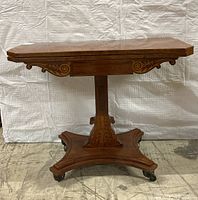 Full front view of closed table showing top, inlay apron and pedestal base on caster wheels