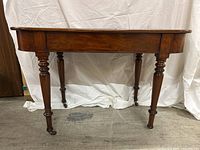 Front left three-quarter view showing turned legs, apron and missing caster on rear left leg