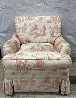 Front view of toile lounge chair showing overall shape, upholstery pattern and skirted base