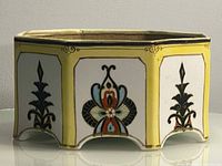 Side view of octagonal porcelain bonsai planter showing decorative panels and footed base