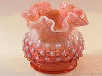 Close-up image showing the hobnail texture and ruffled edge of the cranberry opalescent Fenton glass vase.