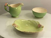 Photo showing a Royal Winton green ceramic creamer, round sugar bowl, and a shallow candy dish with scalloped edges, all accented with floral detail and gold trim.