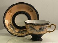 Full view of teacup and saucer showing color scheme, dragon motifs and gold trim