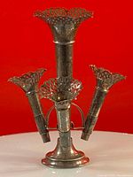 Front angle showing the main trumpet vase with three smaller trumpet vases attached, all silver plated with openwork rims.