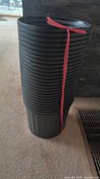 Stack of 25 black plastic soft pots secured with red strap.