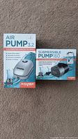 Air pump and submersible pump boxes showing product name and specifications.