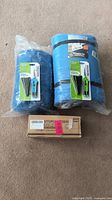 Photo showing sleeping pad, sleeping bag, and boxed pruning shears arranged on carpet.