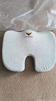Top view of light grey desk chair cushion showing U-shaped cutout and OVYNERISN logo