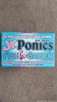 Front packaging of Jr. Ponics Fish Garden kit, showing brand name, tagline about first aquaponics garden for kids, and colorful underwater cartoon design.