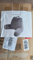 Closed cardboard box with printed image of the gray Millard Reading Pillow taped on the front.