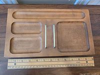 Top-down view showing the five compartments of the wooden desk organizer placed next to a ruler for size reference.