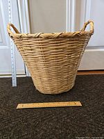 Front and side view of large woven basket with two handles and measurement rulers for scale.