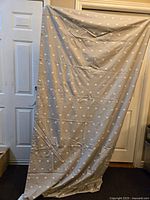 Full view of one gray curtain panel with white elephant print, hanging vertically against door background showing overall fabric and pattern.