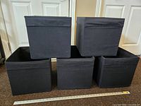 Five black Ikea Drona storage boxes arranged with three on bottom and two on top, showing the front and side view.