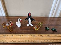 Full lot of six Murano glass animal figurines on wooden surface with ruler for scale