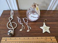 Wide view of lot showing all six musical-themed holiday ornaments arranged on wood surface with ruler for scale.