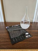 Storm glass with crystals inside and instruction sheet behind