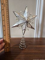 Full view of the vintage mother of pearl star tree topper next to a ruler showing approx 7 inch height