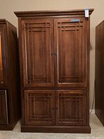 Front view of wooden Arts & Crafts style armoire showing decorative panels and wood finish