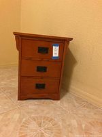 Front view of the nightstand showing its three drawers, metal handles, and wood finish.