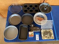 Top view showing full assortment of baking pans and molds on blue surface.