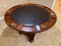 Photo showing the game side of the round wooden table with padded playing surface, cup holders, and card slots.