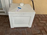 White plastic square garden hose storage box with a removable pyramid lid, surface has minor dirt and scuff marks. Dimensions approximately 17 x 17 x 16 inches.